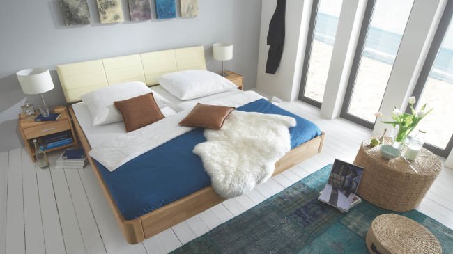 flaches Bett aus Holz mit blauem Laken